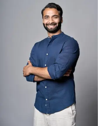 Smiling man in blue shirt with arms crossed