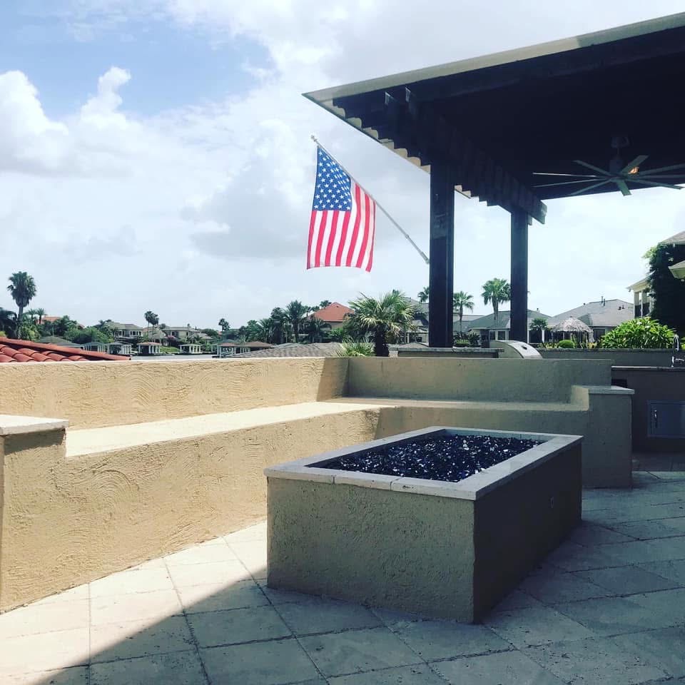 Covered patio with modern outdoor fire pit and American flag in background
