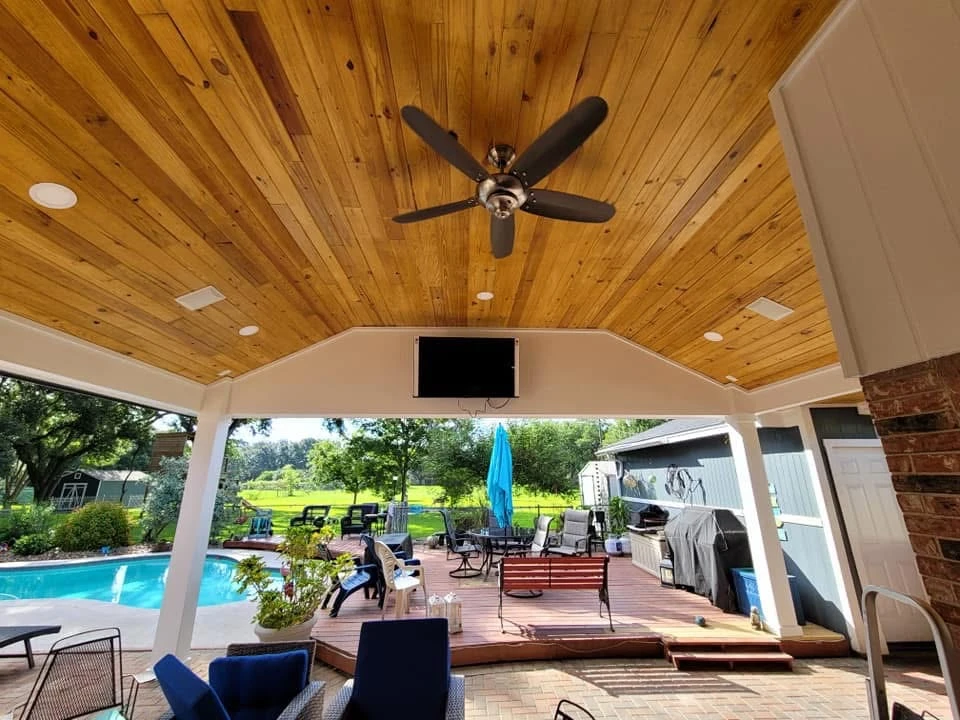Poolside patio with wood ceiling, ceiling fan, and lounge area